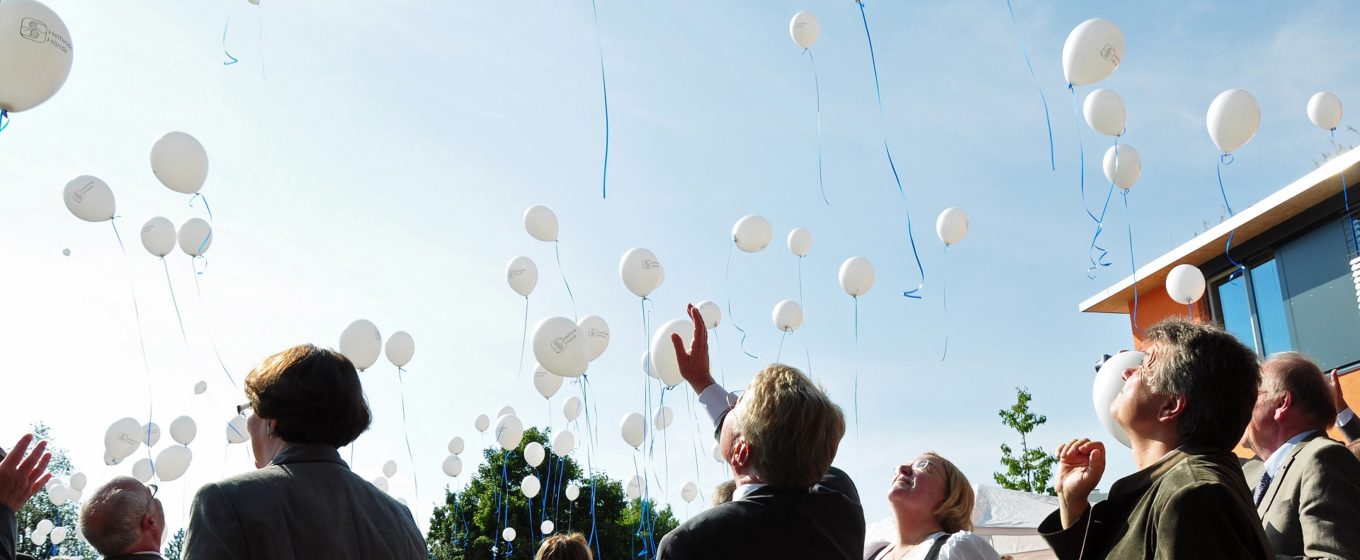 Bei einer Feier von Helfende Hände werden Luftballons steigen gelassen.